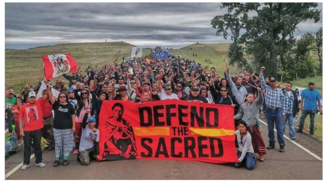 Protesters hold up a "Defend the Sacred" in support of #noDAPL